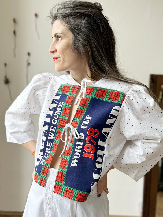 Vicki wears an upcycled Scotland World Cup 1978 teatowel blouse. Looking towards her right with hands on her hips.