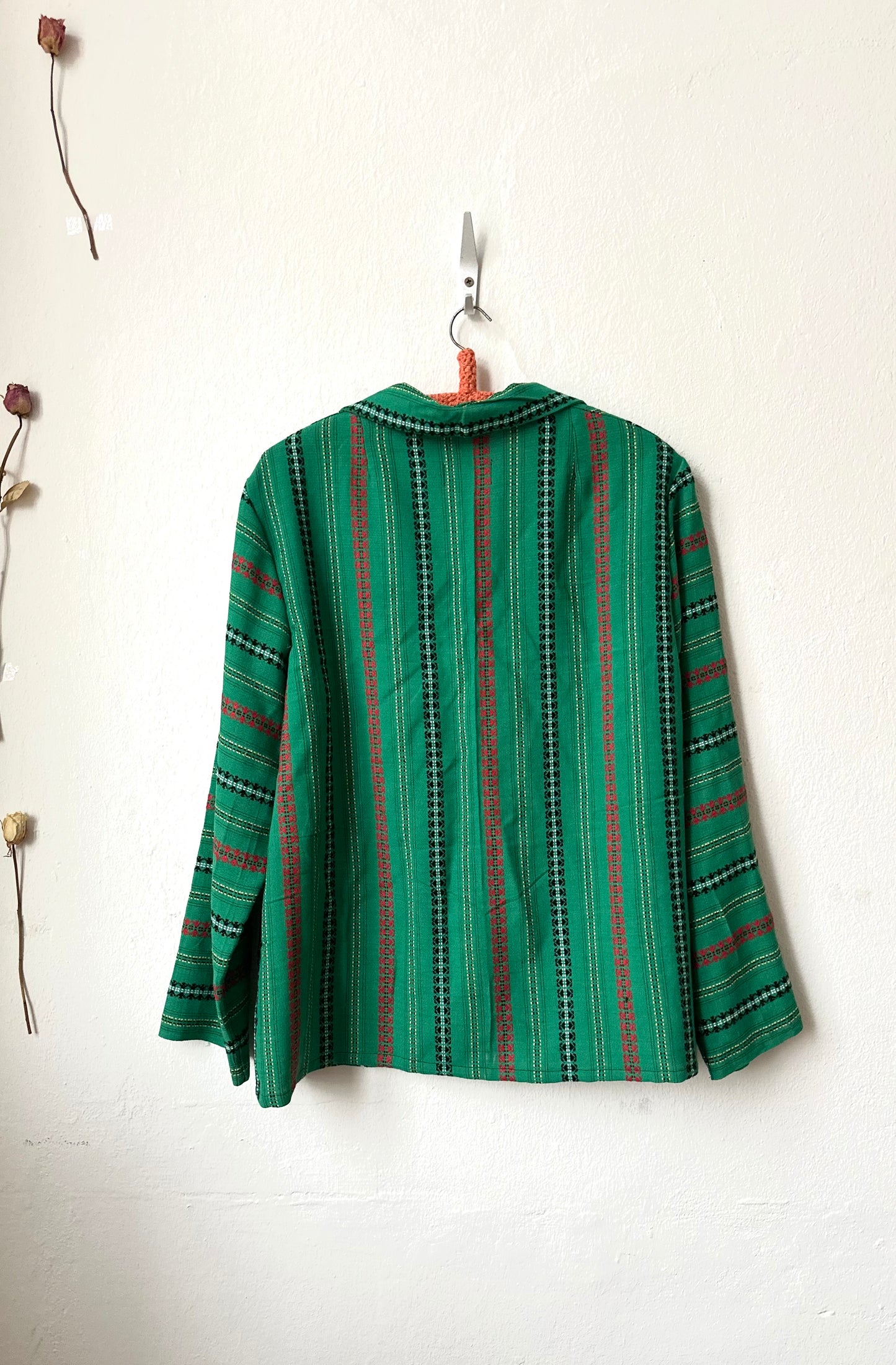 Green and red striped jacket hanging on a white wall