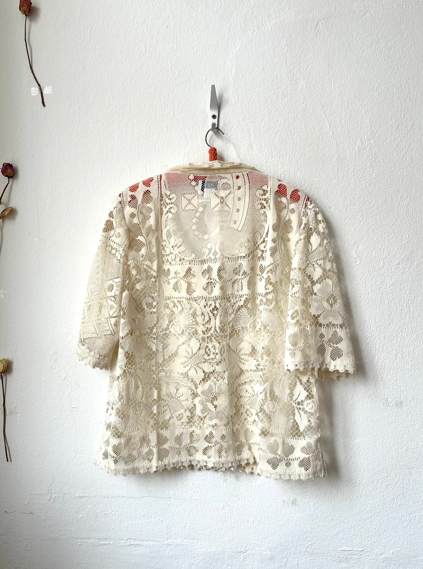 Cream lace top hanging on a white wall
