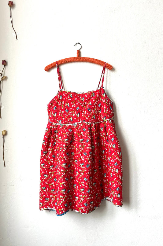 A Red floral print quilted summer dress hangs on the wall.