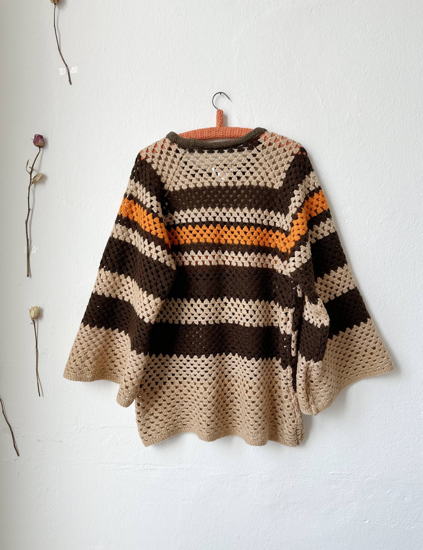 The back view of a brown striped sweater hanging on a wall