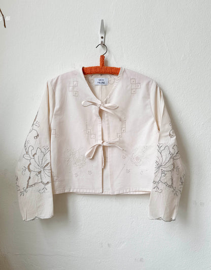 Handmade long sleeve vintage lace and embroidered cotton blouse sourced in Rome, hanging on a wall in Berlin studio