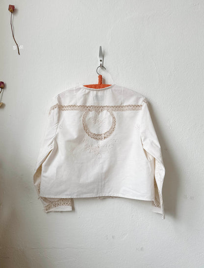Handmade long sleeve vintage lace and embroidered cotton blouse sourced in Rome, hanging on a wall in Berlin studio