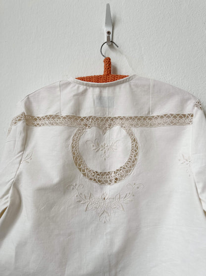 Handmade long sleeve vintage lace and embroidered cotton blouse sourced in Rome, hanging on a wall in Berlin studio