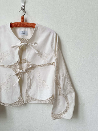 Handmade long sleeve vintage lace and embroidered cotton blouse sourced in Rome, hanging on a wall in Berlin studio