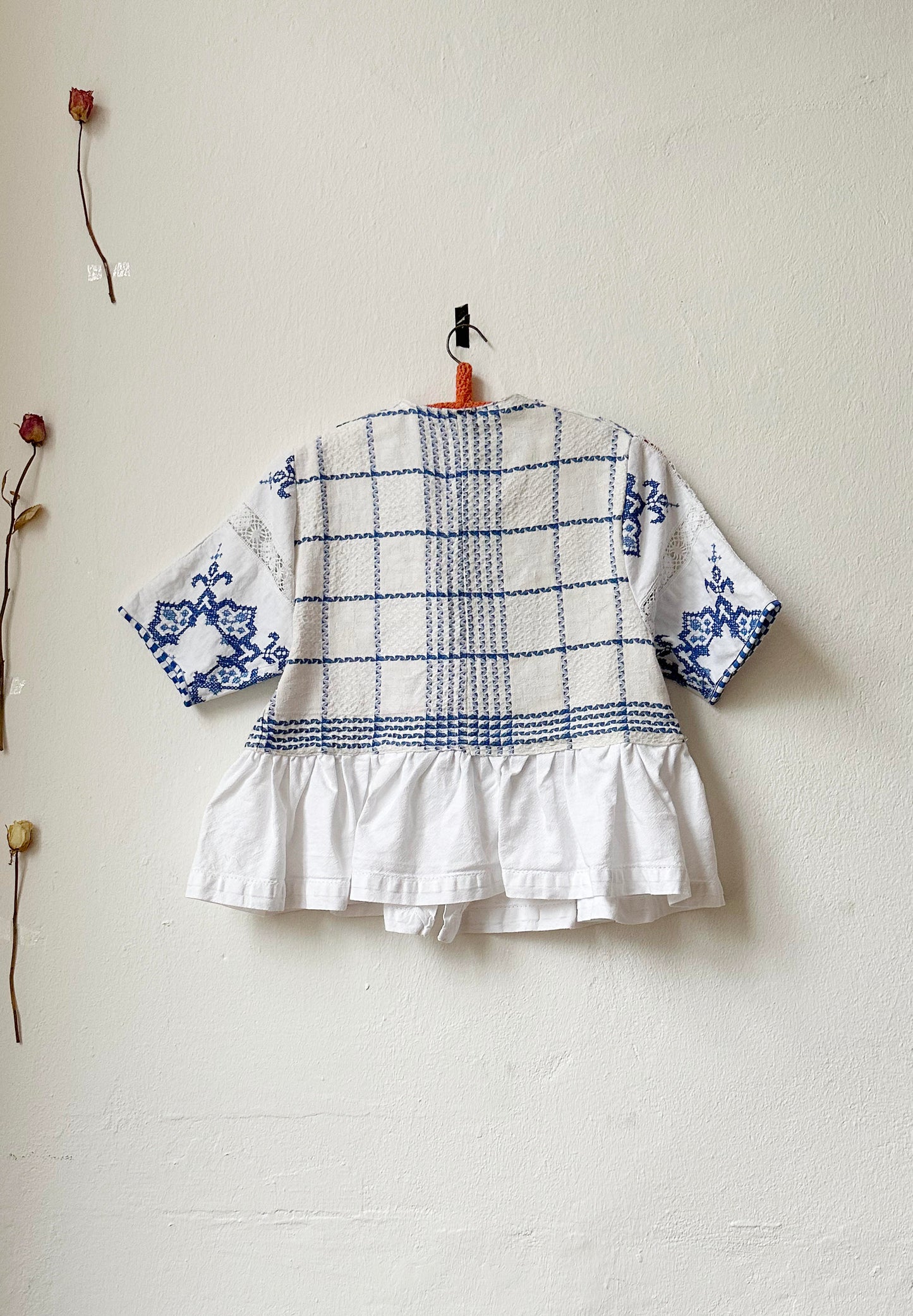 Back view of blue and white check blouse with peplum hem. 