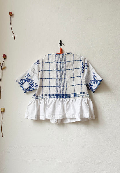 Back view of blue and white check blouse with peplum hem. 