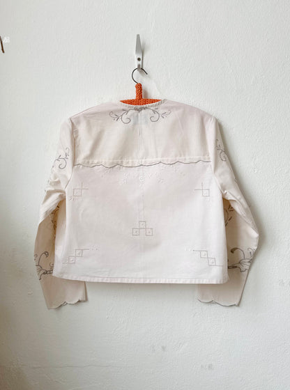 Handmade vintage patchwork embroidered cotton blouse with long sleeves, made from Scottish family tablecloths, hanging on a wall