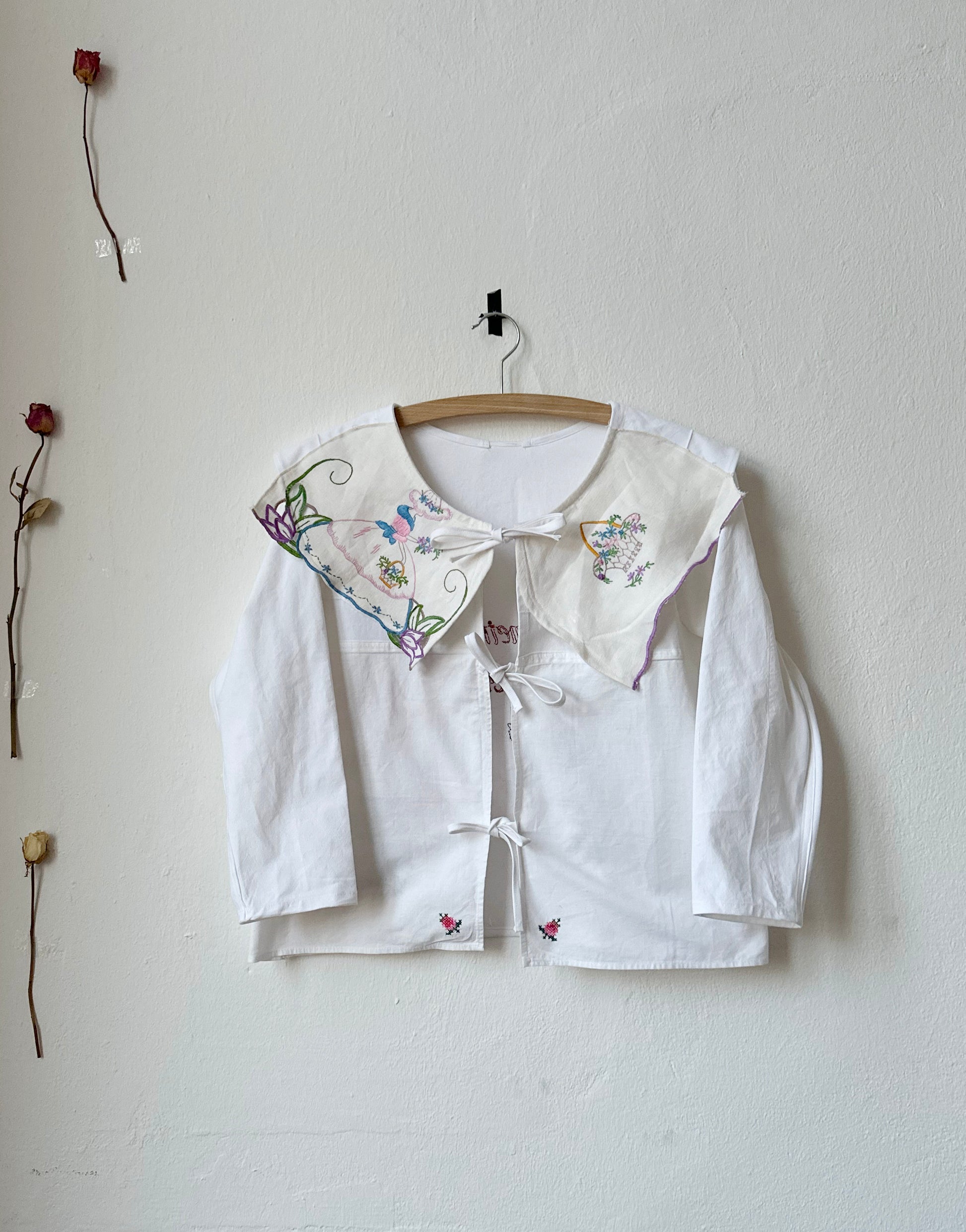 Embroidered white blouse with tie closure, front view.