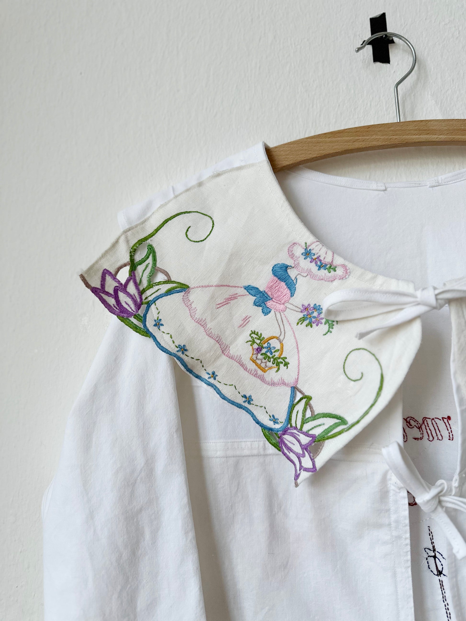 Detailed view of embroidered collar on white blouse.