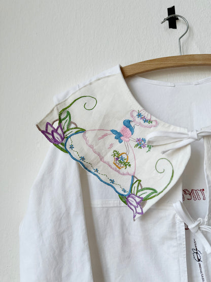 Detailed view of embroidered collar on white blouse.