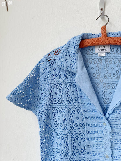 Light blue lace blouse on a hanger against a white background