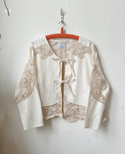 Off-White lace blouse on a hanger against a white wall