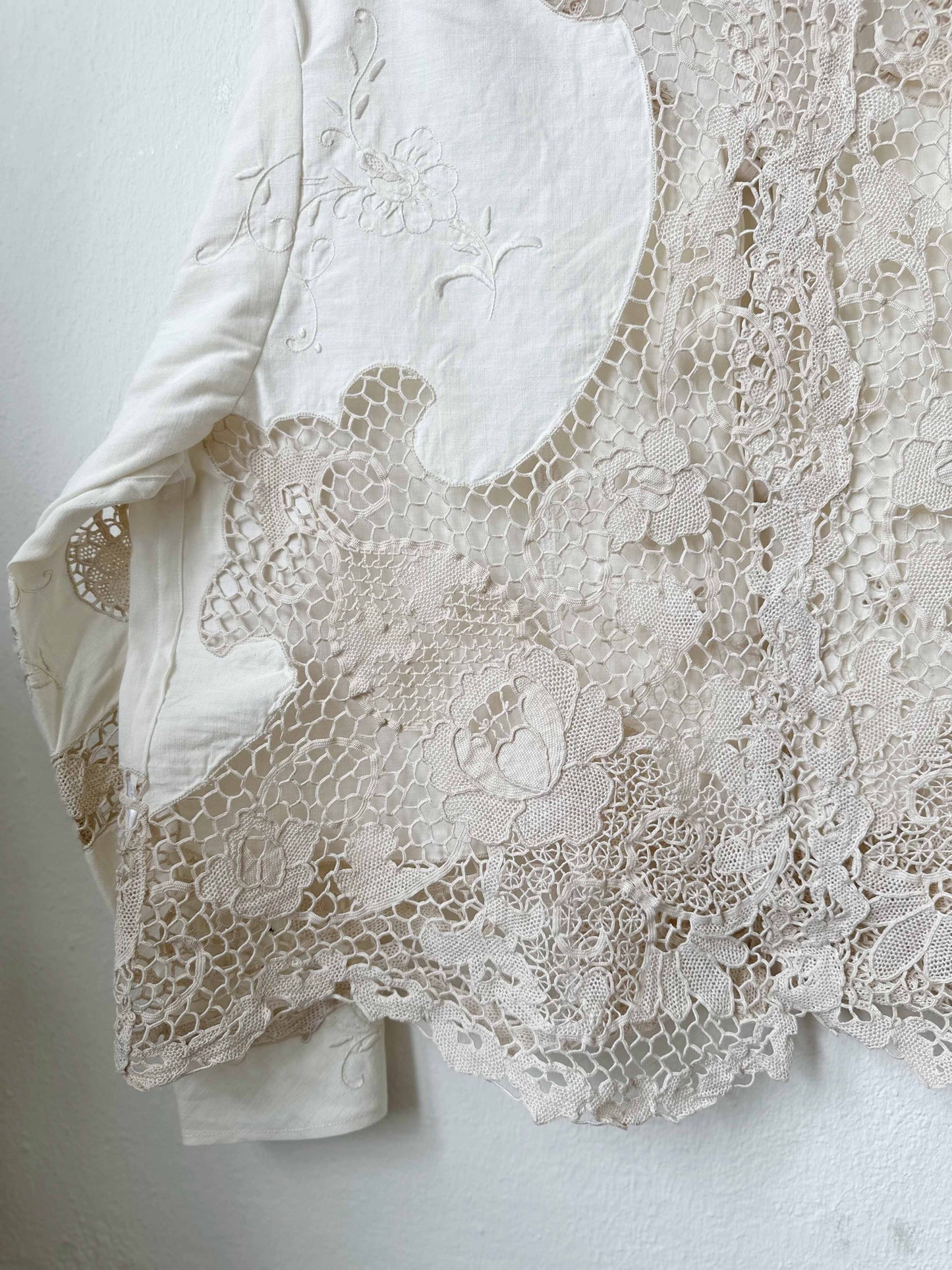 Handmade vintage lace blouse with long sleeves hanging on a wall, made from a Rome flea market tablecloth
