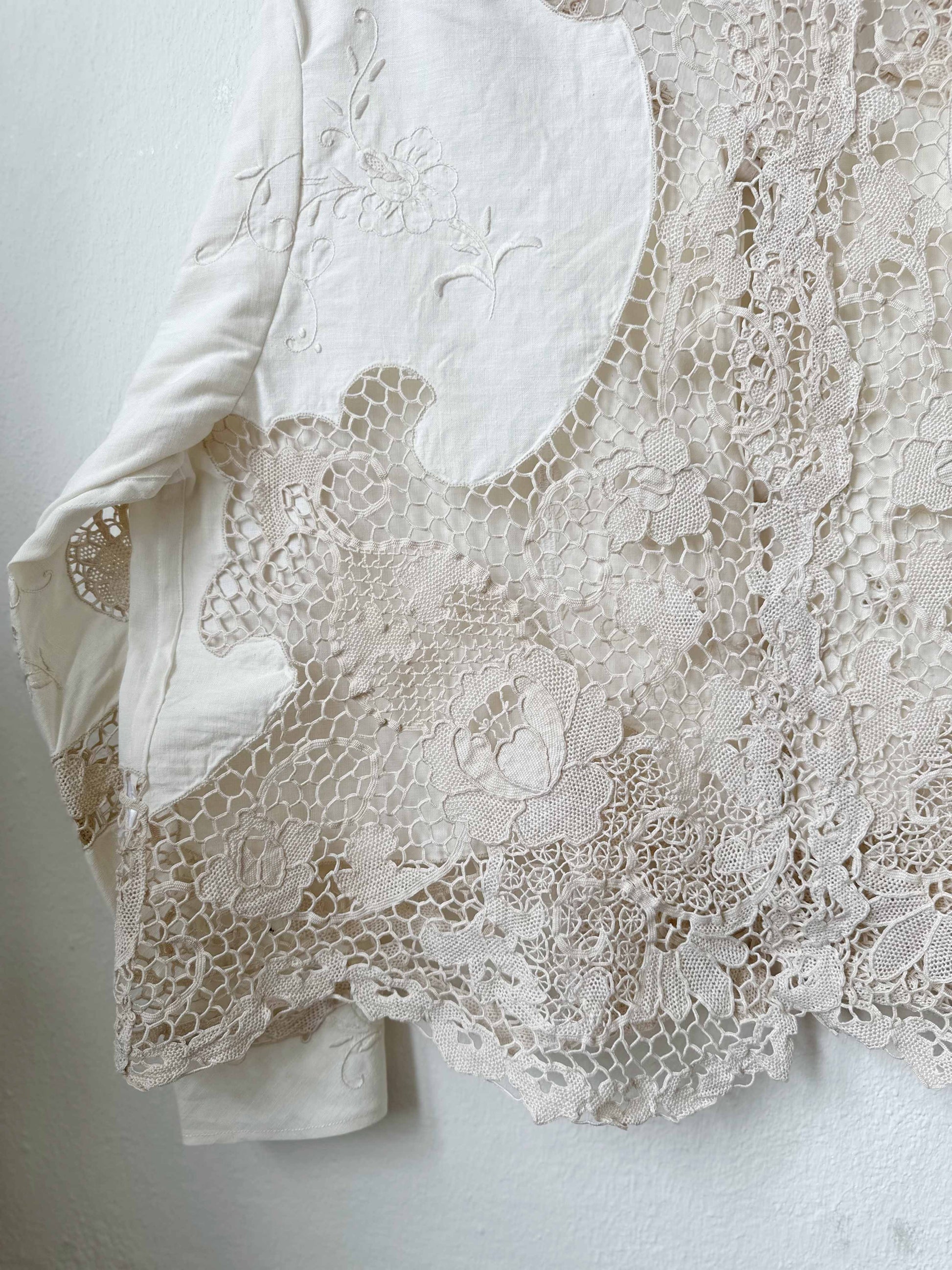 Handmade vintage lace blouse with long sleeves hanging on a wall, made from a Rome flea market tablecloth
