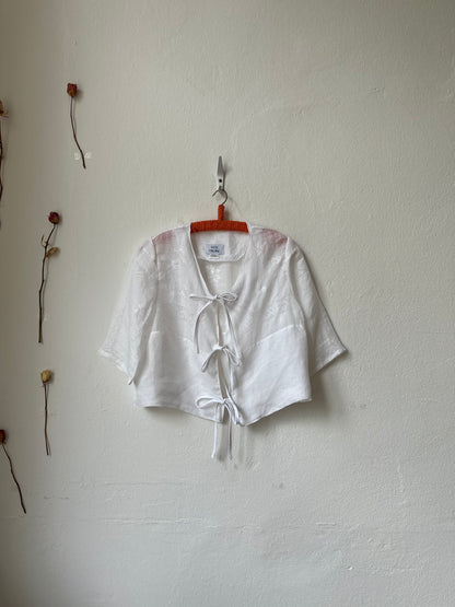 White shirt on a hanger with a visible tag on a white wall