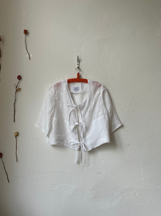 White shirt on a hanger with a visible tag on a white wall