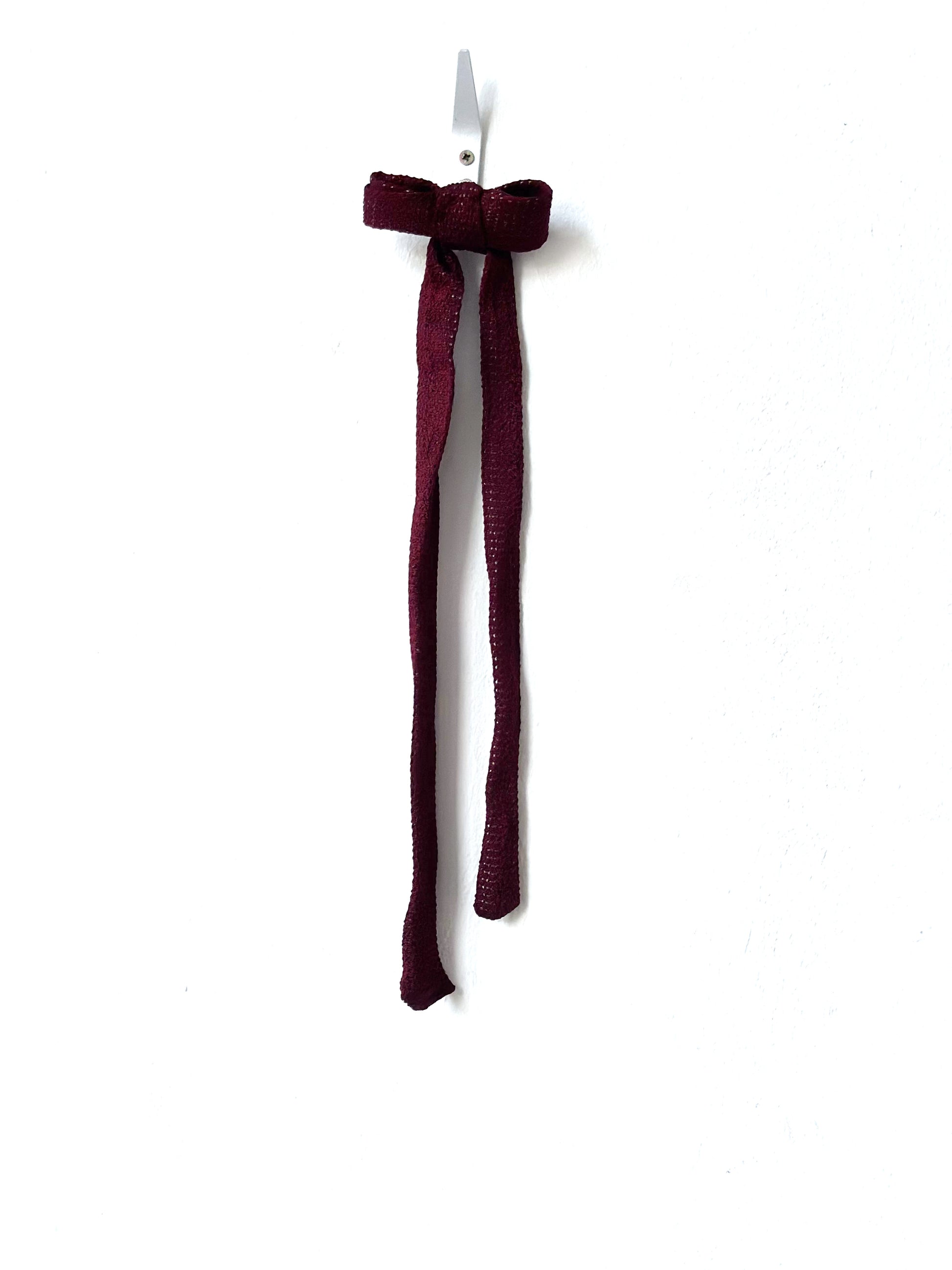 Burgundy bow hair clip on a white background
