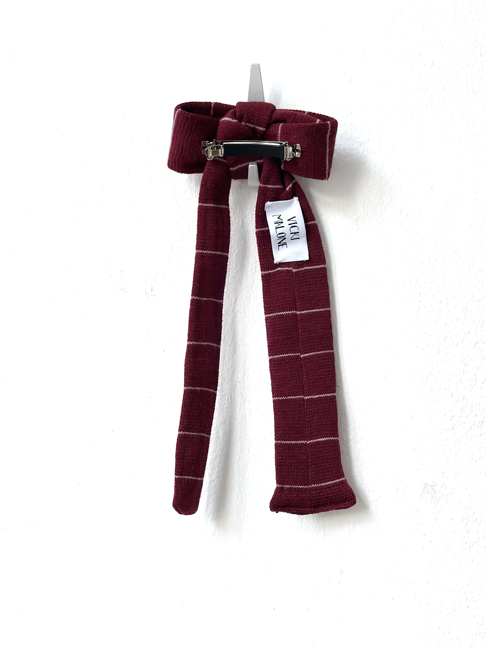 Striped bow hair clip with a visible brand tag on a white background