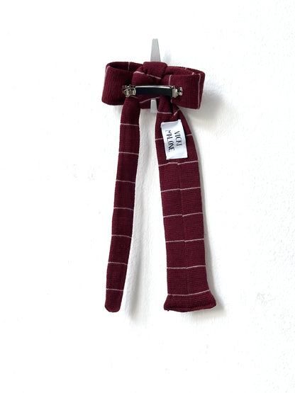 Striped bow hair clip with a visible brand tag on a white background