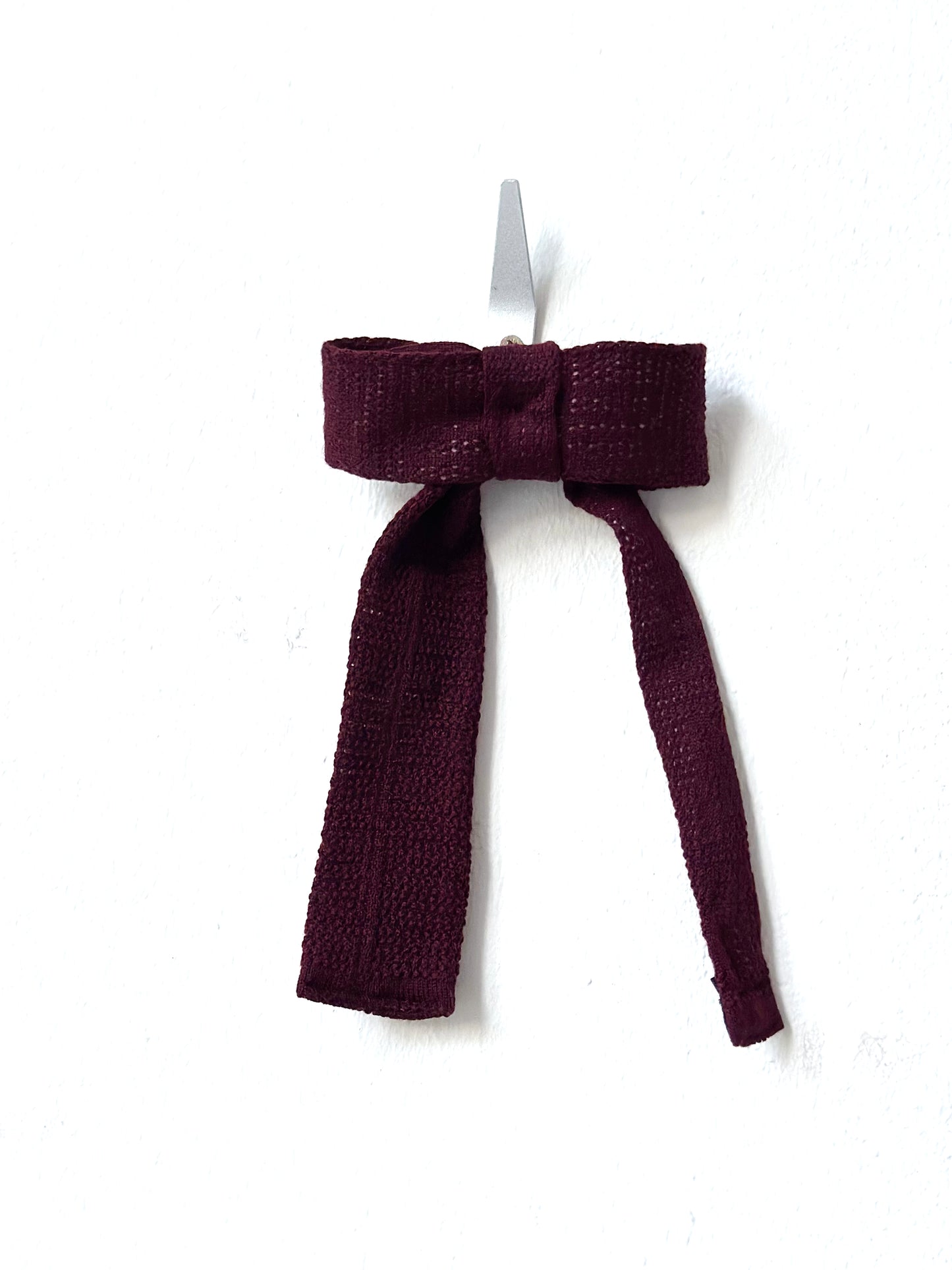 Burgundy bow hair clip on a white background