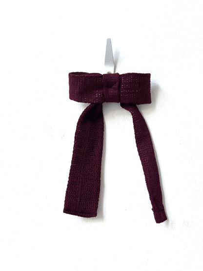 Burgundy bow hair clip on a white background