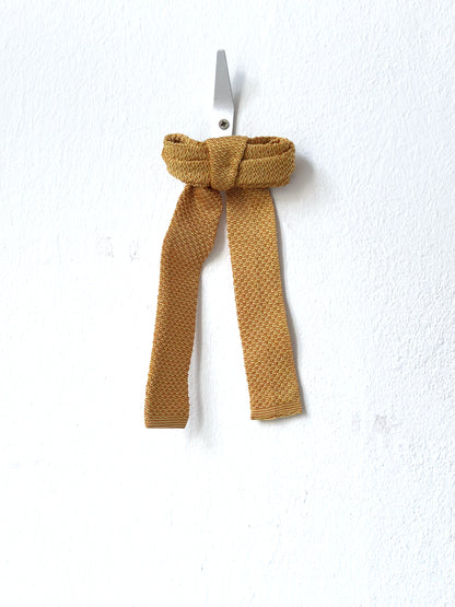 Mustard-colored knitted bow tie on a white background