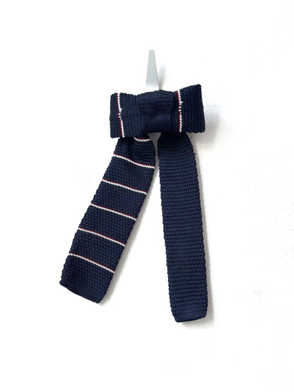 Navy blue knitted bow tie with pink stripes on a white background