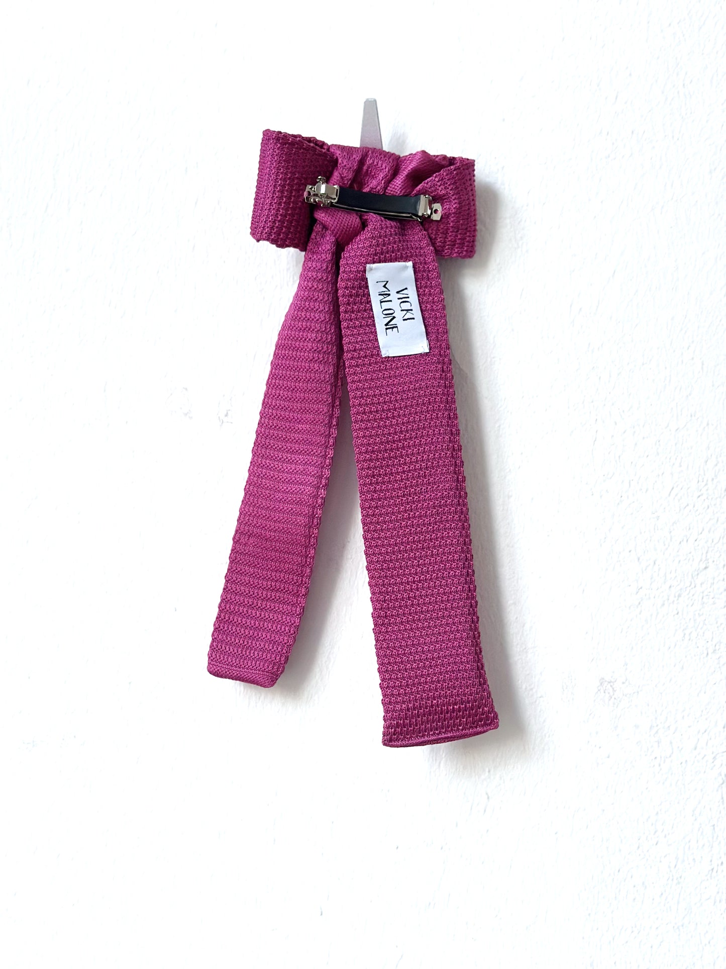 Pink bow barette back with a tag on a white background