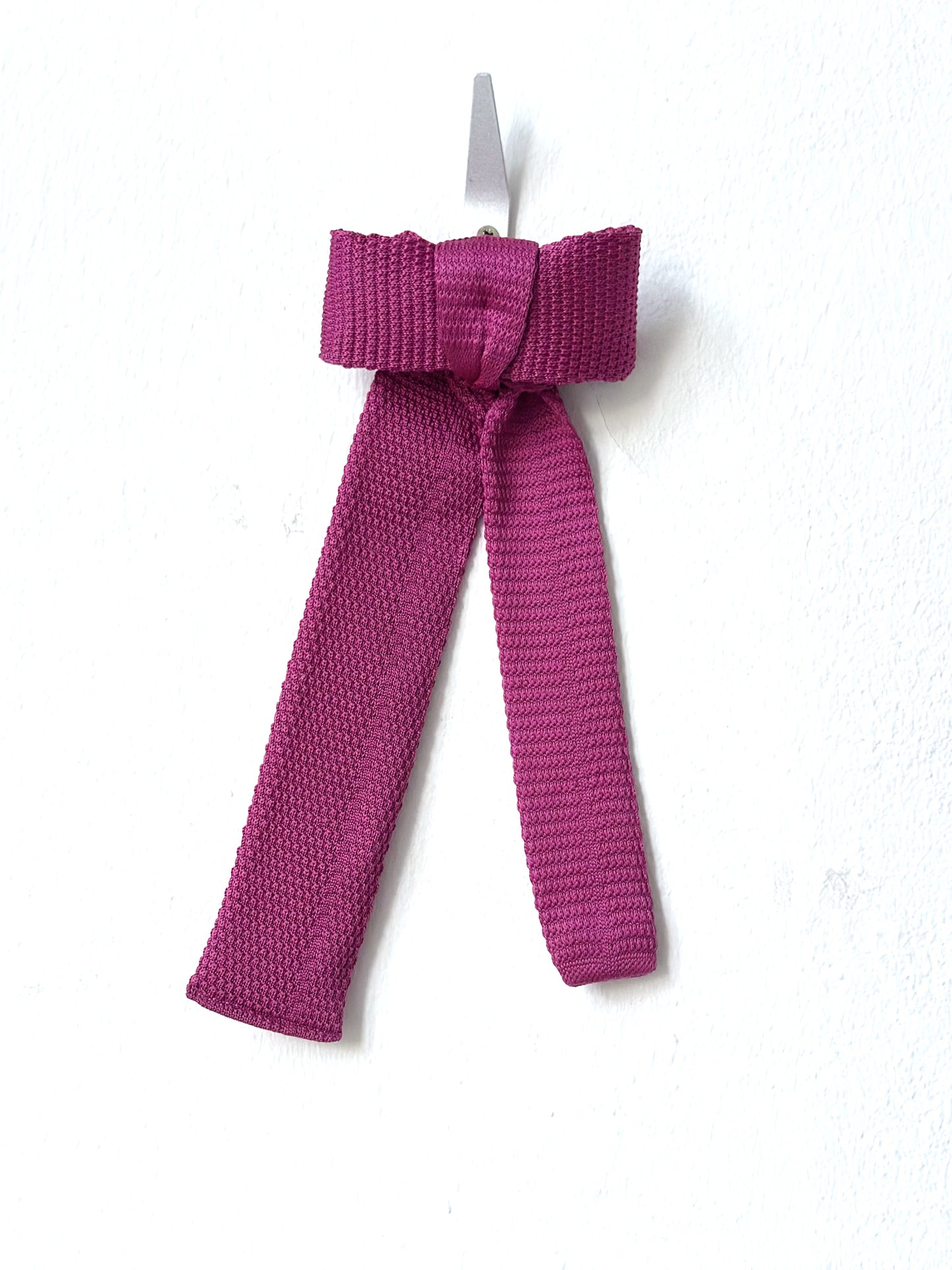 Pink knitted bow barette on a white background