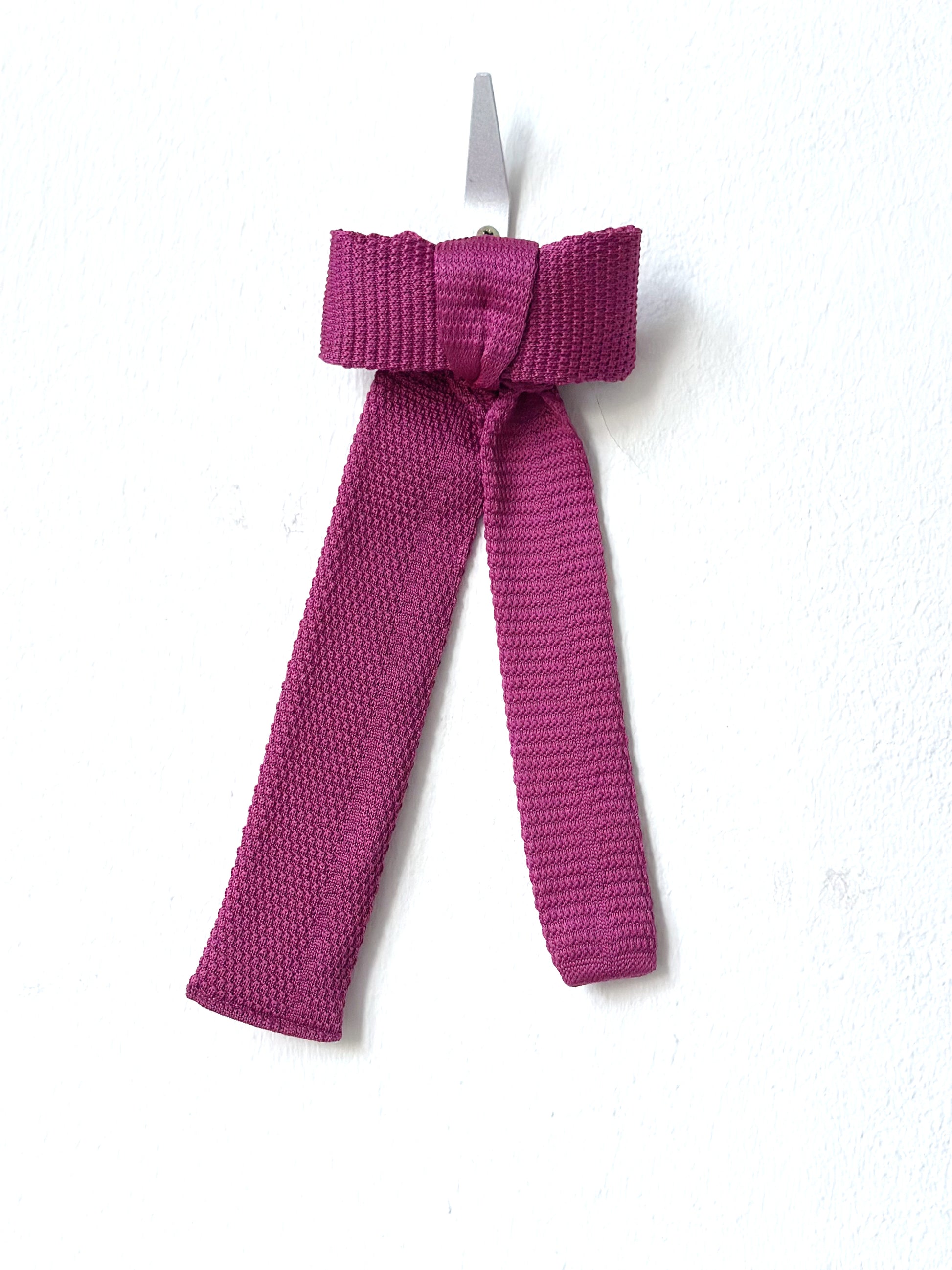 Pink knitted bow barette on a white background