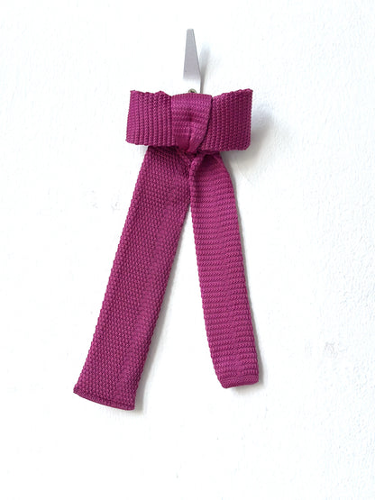 Pink knitted bow barette on a white background