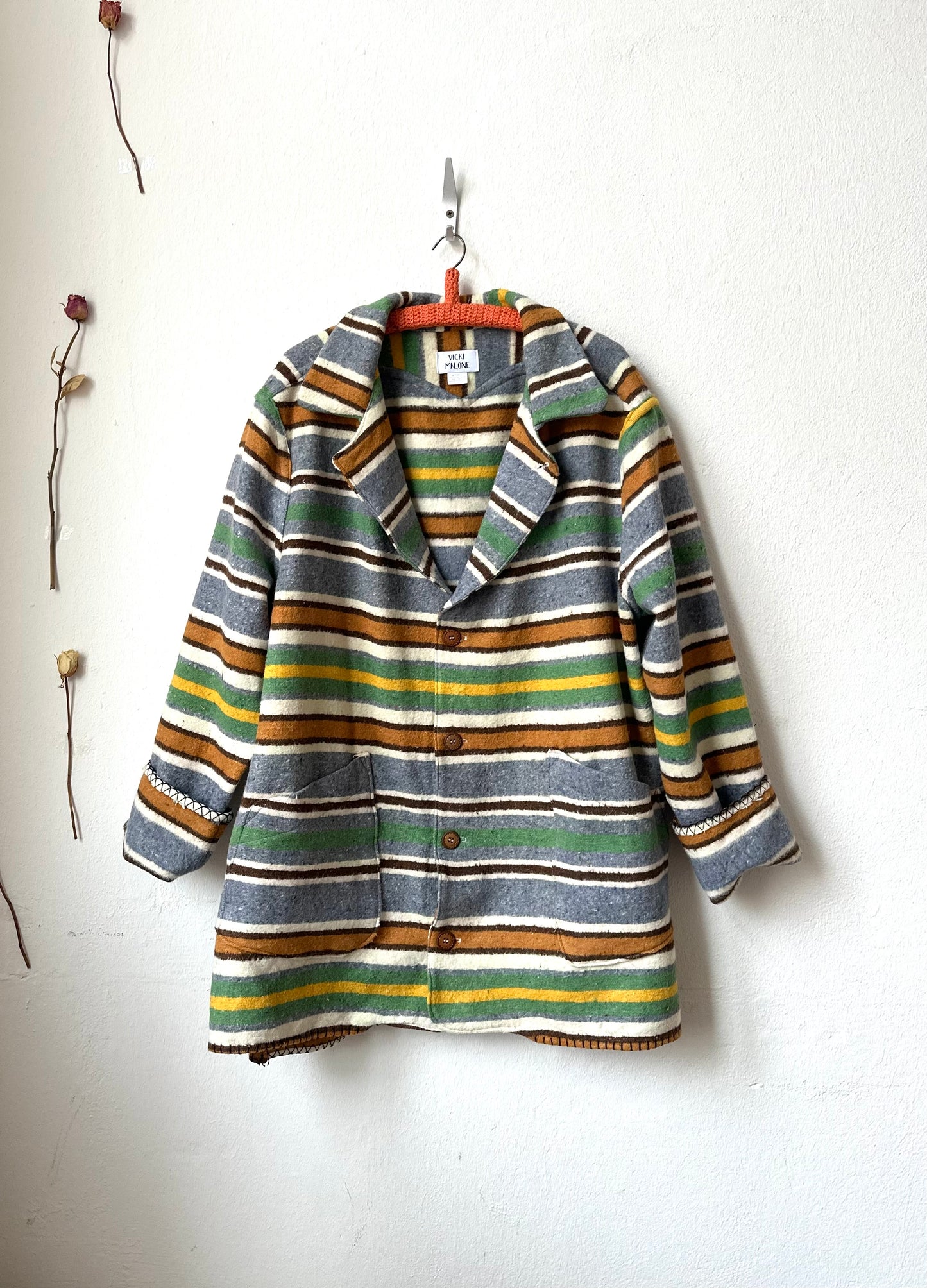 Striped jacket hanging on a white wall with minimal decor