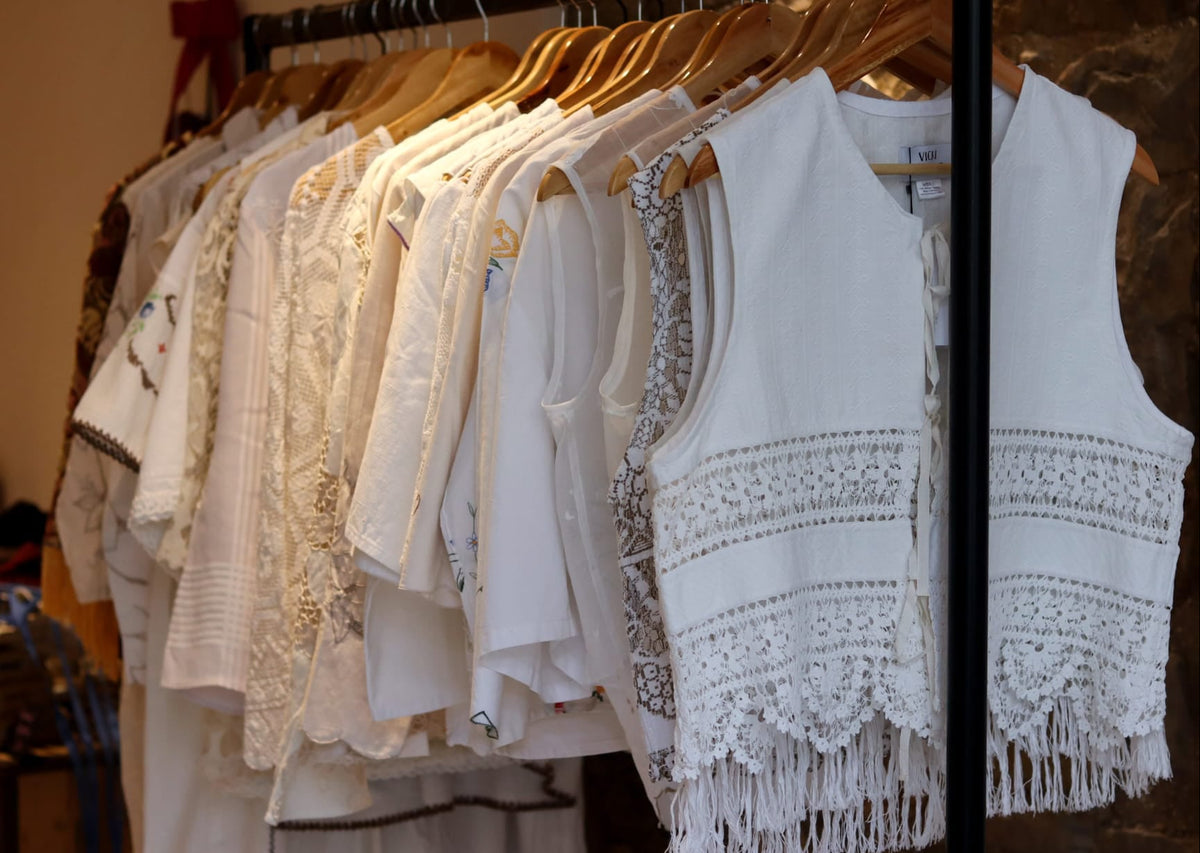 Rack of white and beige tops with lace details in a store setting