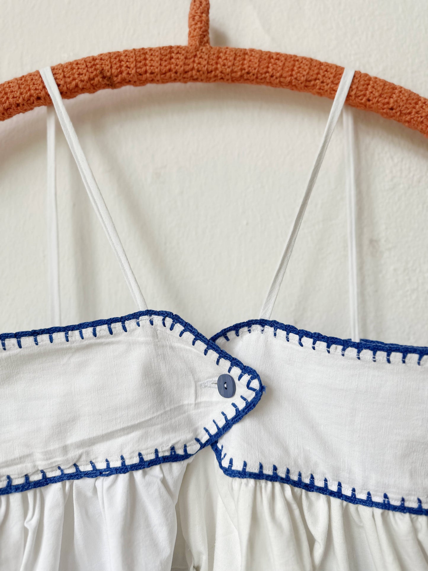 White dress with blue patterns on a hanger against a white background