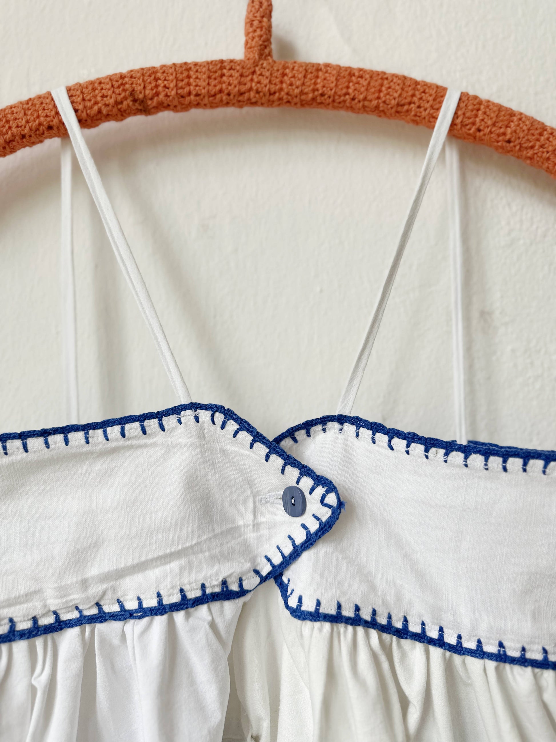 White dress with blue patterns on a hanger against a white background