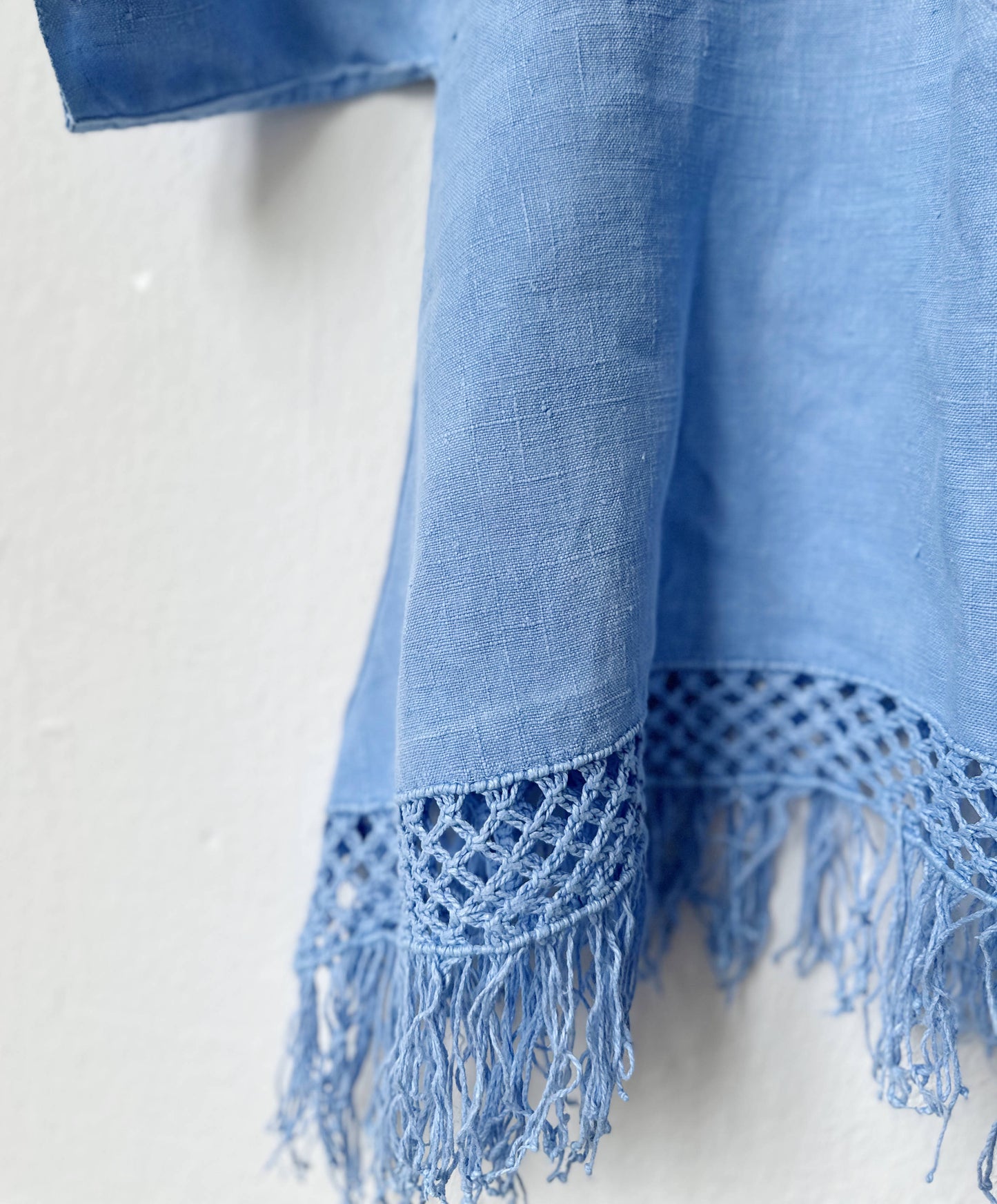 Blue top with fringes and textured edge on a white background
