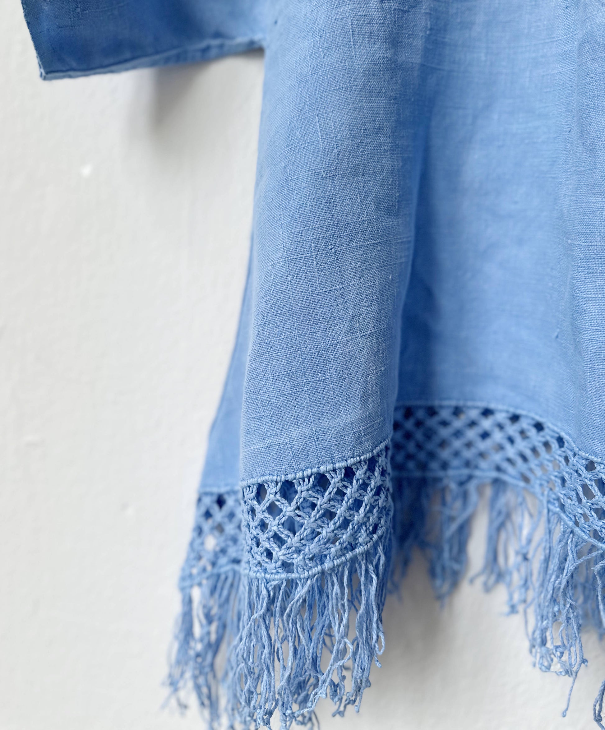 Blue top with fringes and textured edge on a white background