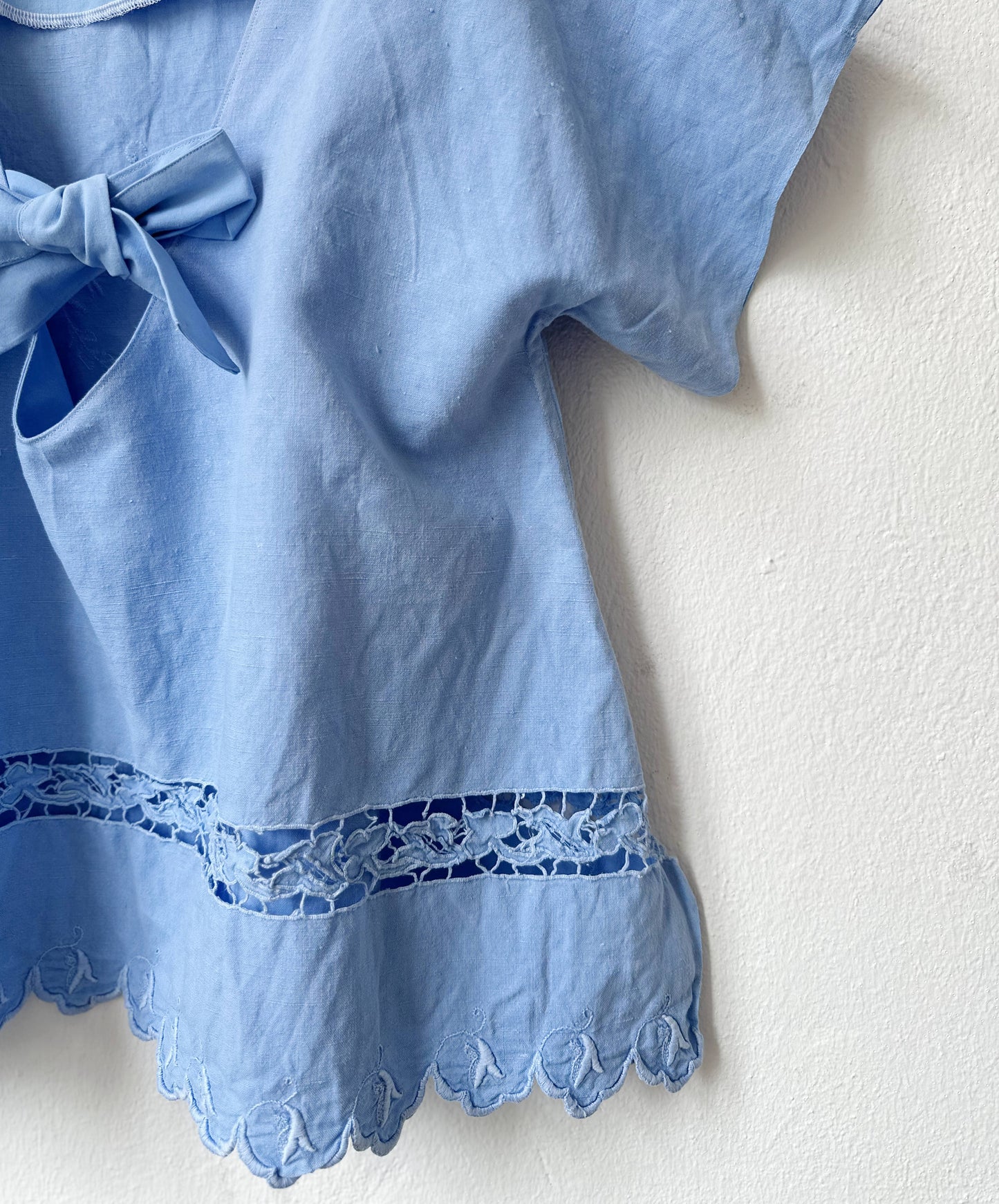 Light blue dress with lace trim and a bow detail on a white background