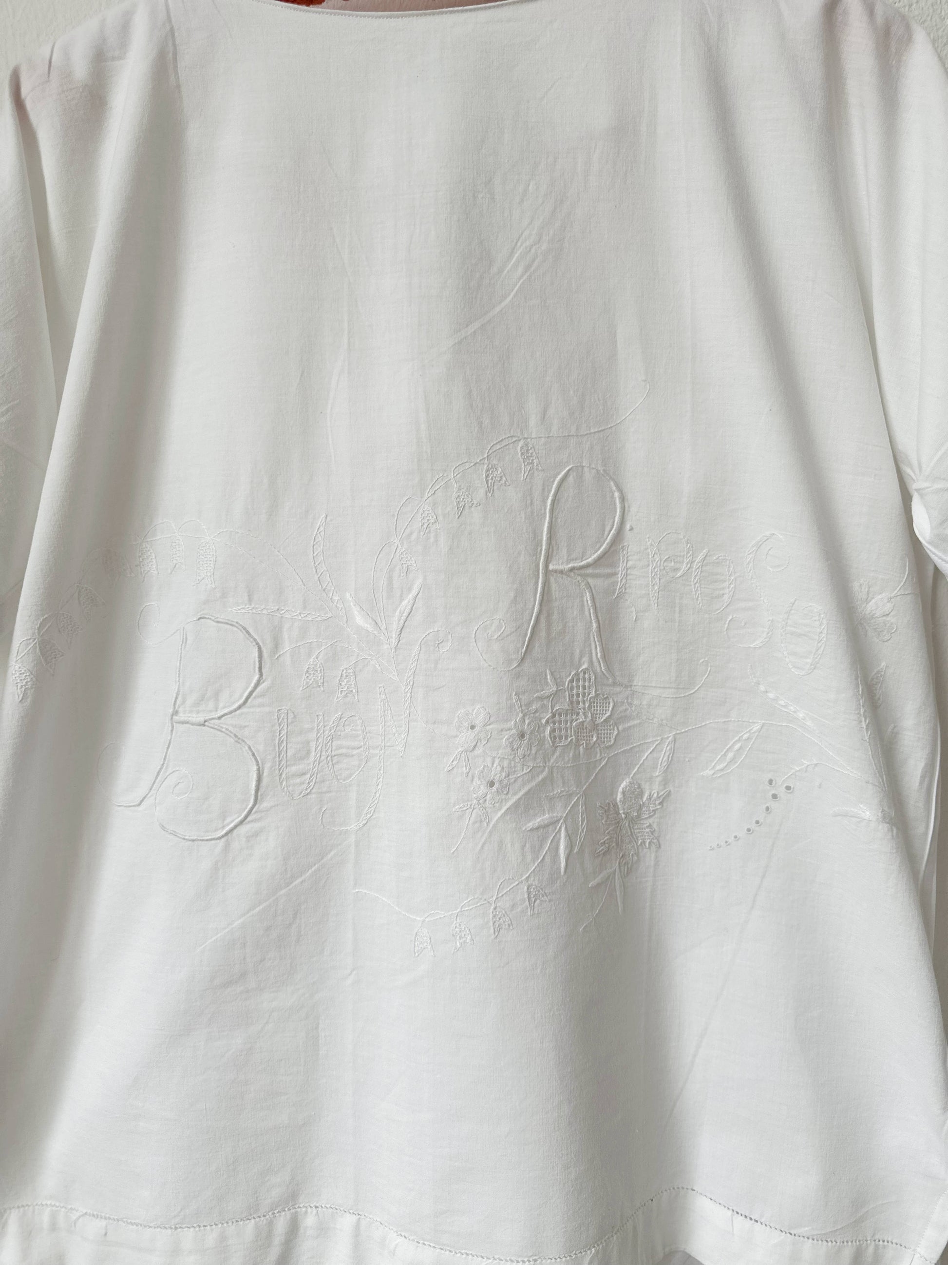 White fabric with embroidered Buon Riposo' on a plain background
