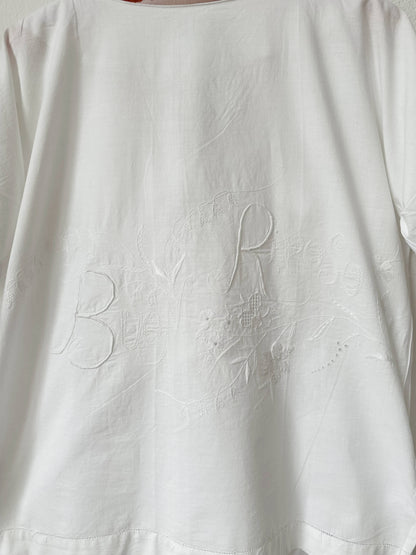 White fabric with embroidered Buon Riposo' on a plain background