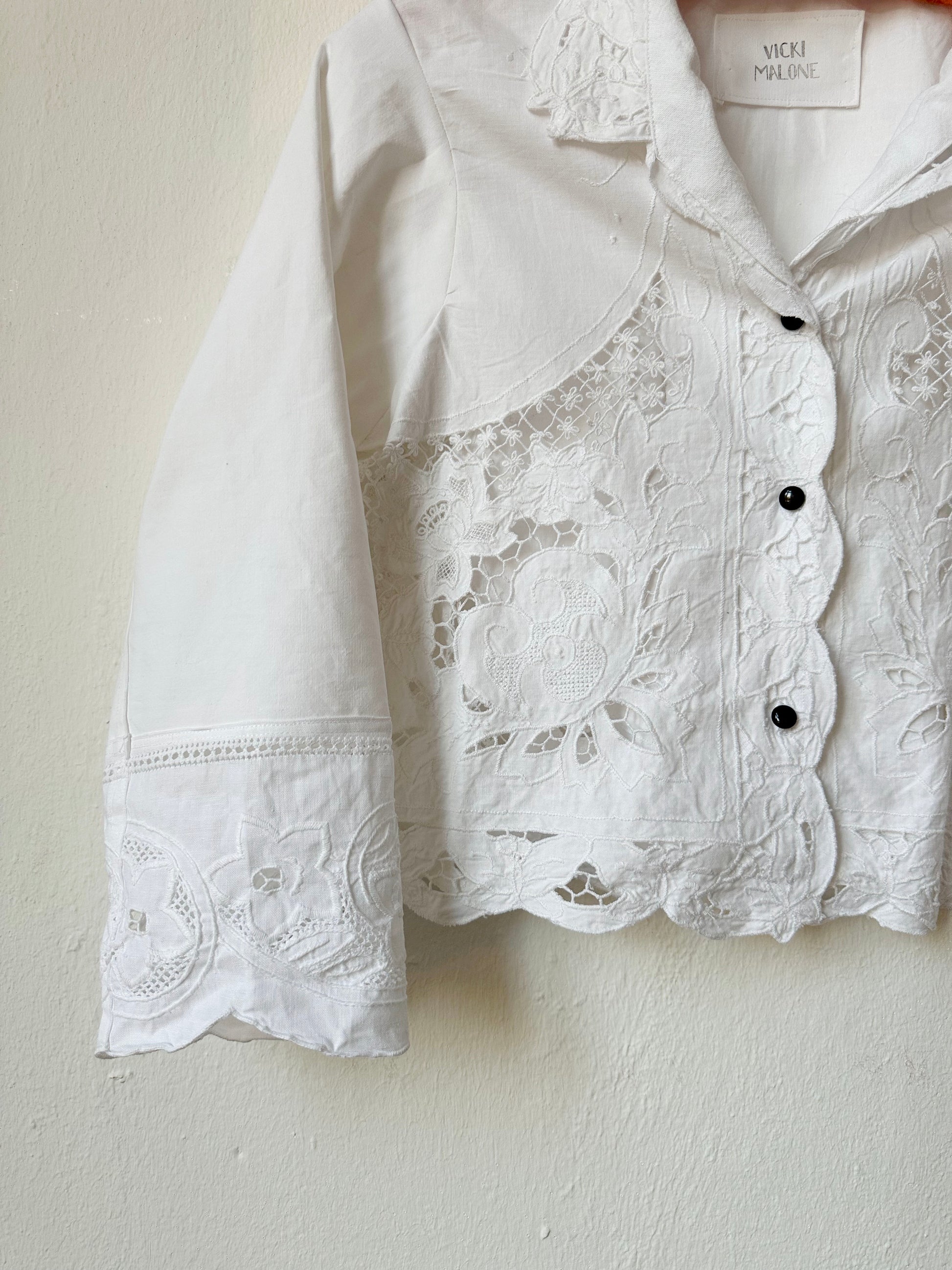 Detailed view of white lace blouse with buttons. 