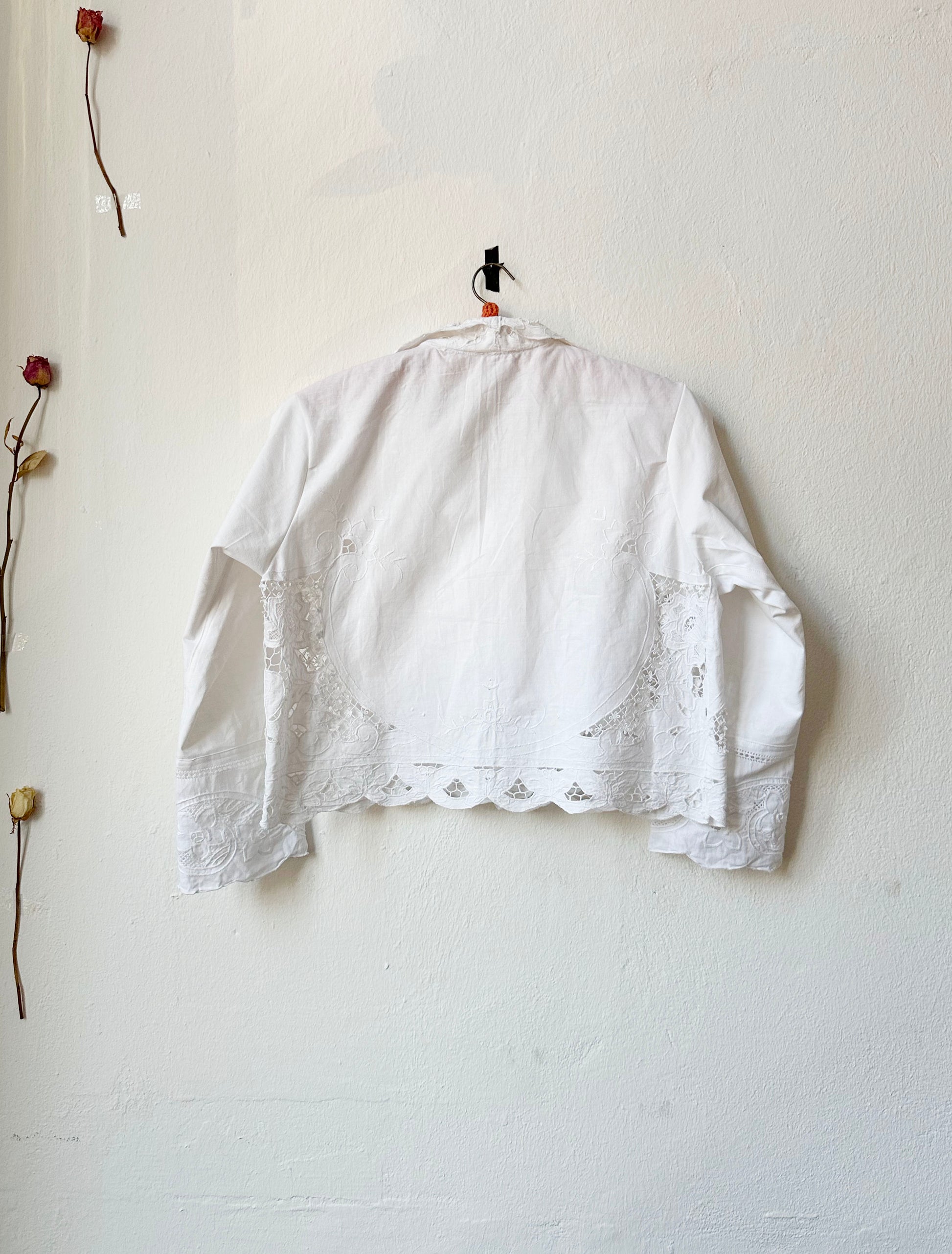 Back view of white lace blouse hanging on the wall. 