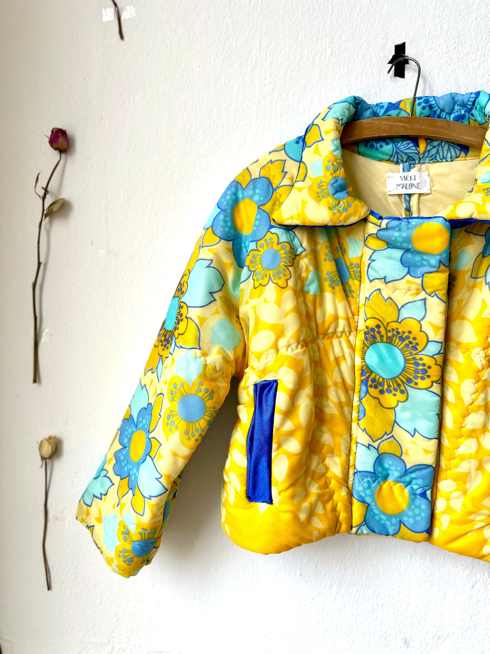 A vintage DDR yellow and blue duvet jacket hangs on the wall.