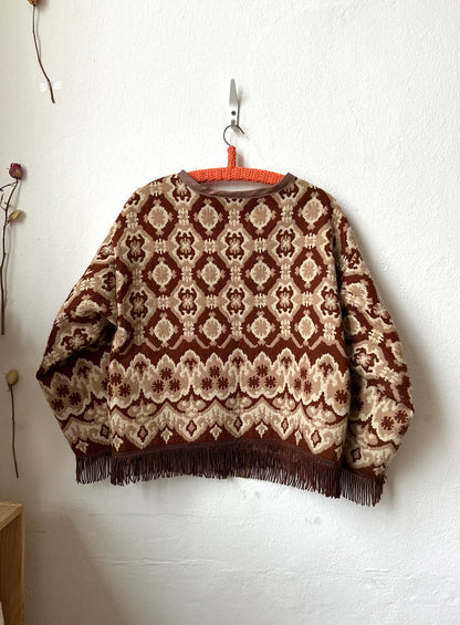 Patterned jacketwith fringes hanging on a white wall