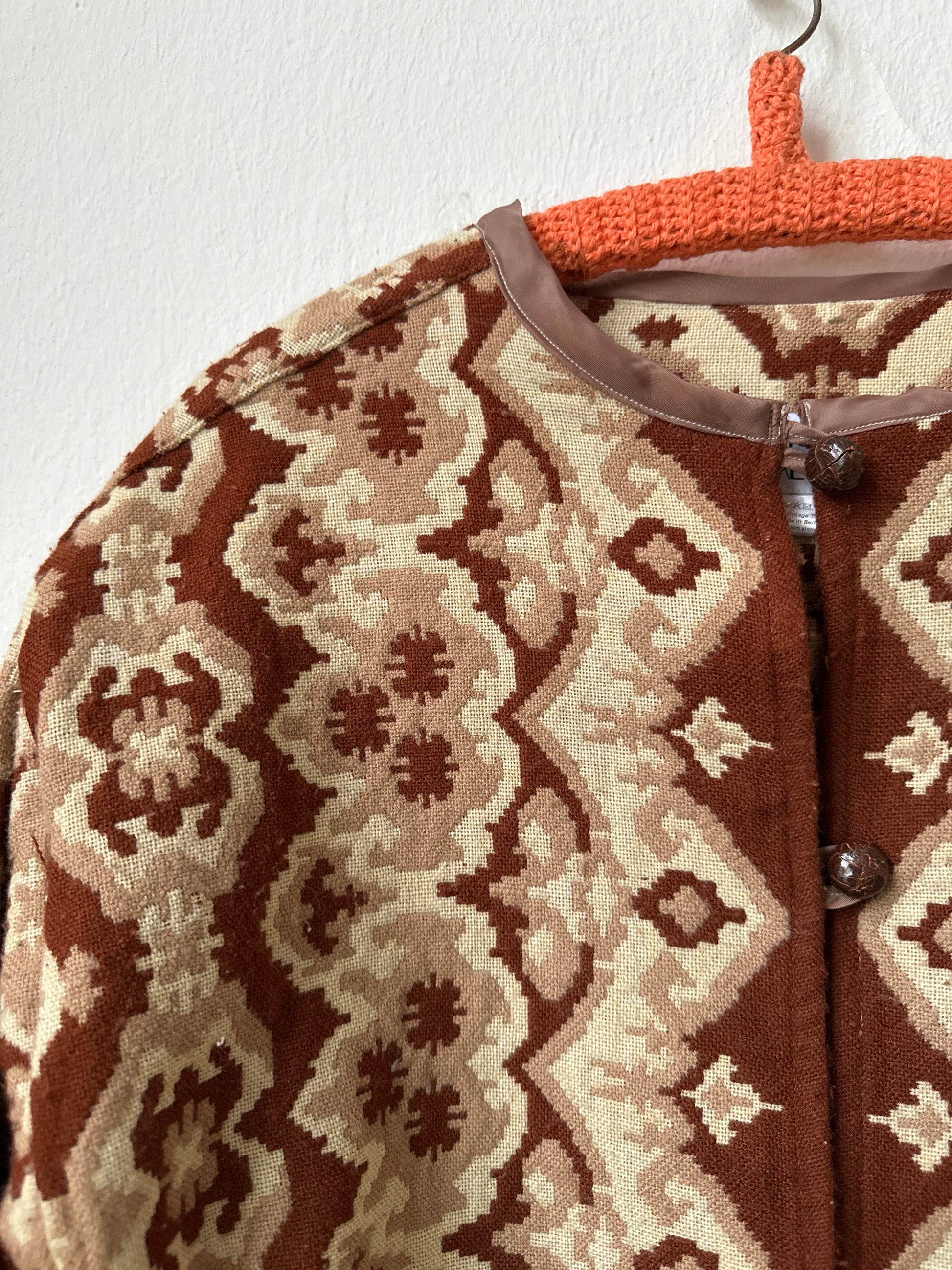 Close-up of a patterned jacket neckline hanging on a white wall.