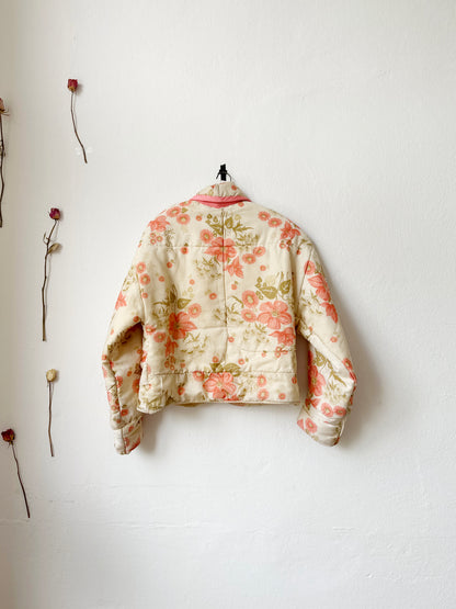 A back view of a quilt floral pattern jacket hanging on a wall.