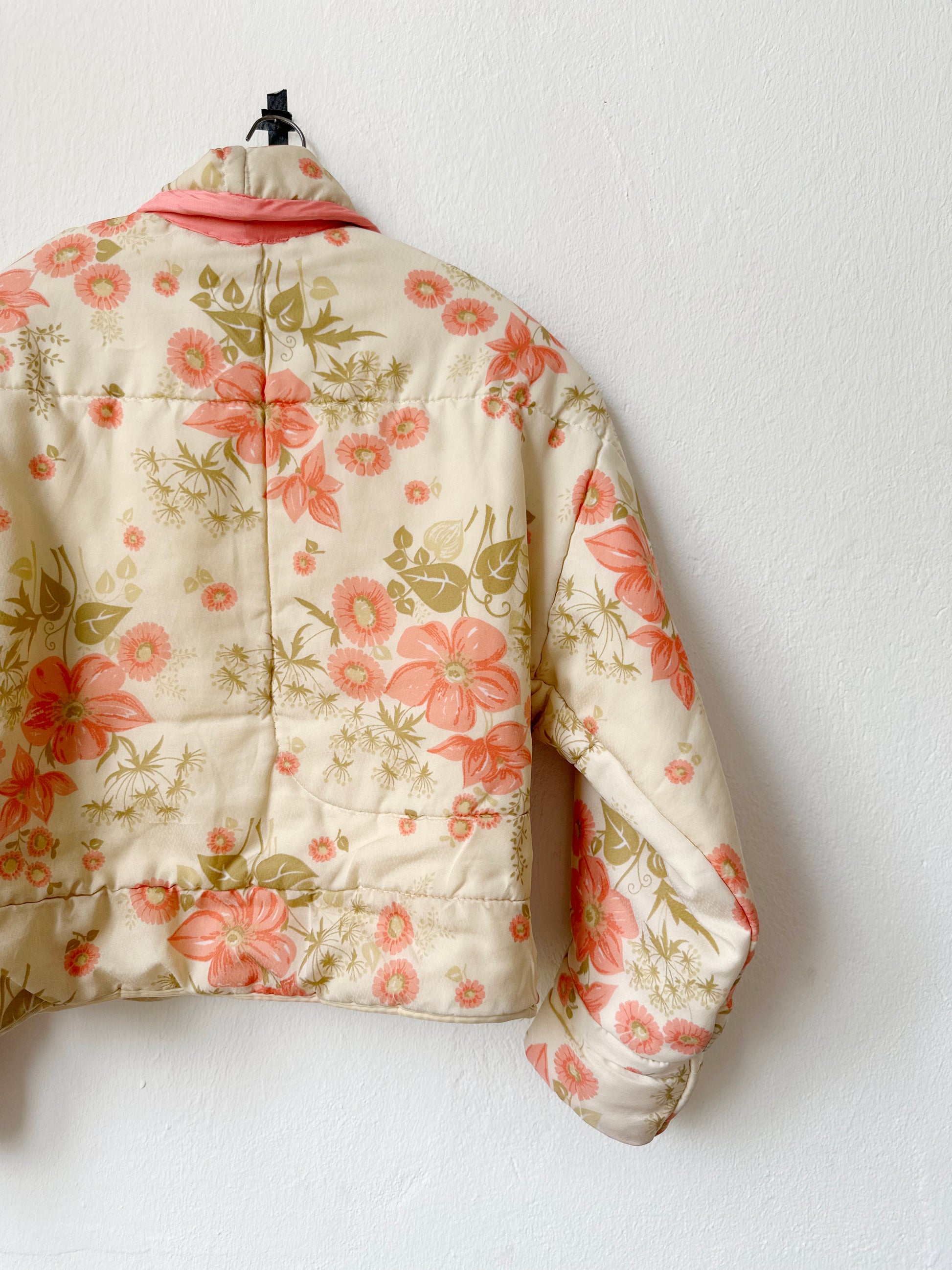 A peach floral pattern quilt duvet jacket hangs on a wall.