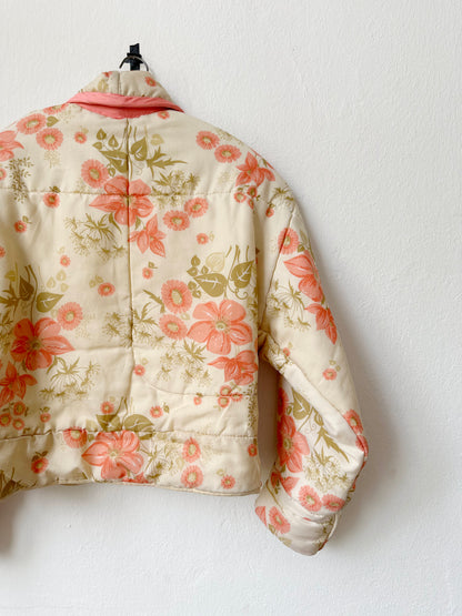 A peach floral pattern quilt duvet jacket hangs on a wall.