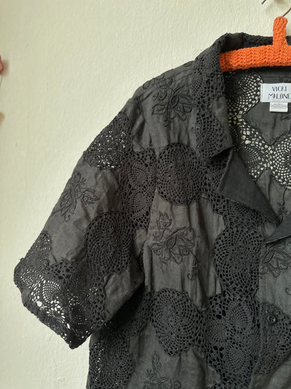 Black embroidered shirt on a hanger against a white wall